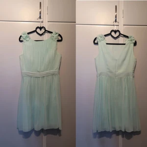 Somrig cocktailklänning - Lårkort cocktailklänning, använd 1 gång vid ett bröllop. Har lite tyll i nederkant på underkjolen som ger ett fint fall på klänningen.   Polyester. Handtvätt.