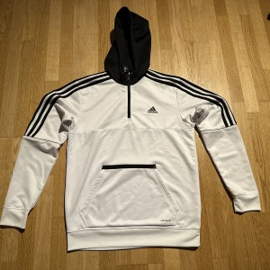 Adidas träningströja - Adidas träningströja vit och svart med luva, använd ca 4 gånger. Storlek M, något stor i storlek så sitter bra på mig med L i vanliga fall. Väldigt fint skick förutom ett märke på magfickan. Kan skickas eller mötas upp i Göteborg.