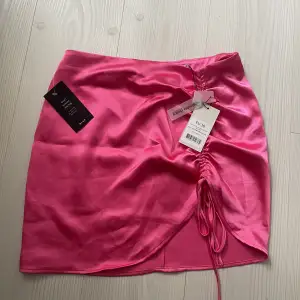Rosa satin kjol med snörning från NA-KD med alla prislappar kvar! Har blivit lite ”uppriven” när den testats men inget man tänker på!