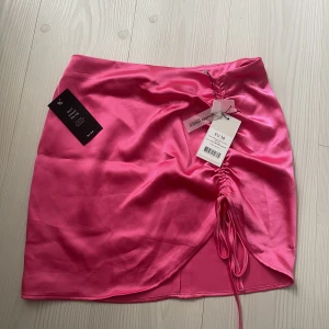Rosa kjol - Rosa satin kjol med snörning från NA-KD med alla prislappar kvar! Har blivit lite ”uppriven” när den testats men inget man tänker på!