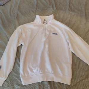 Snx half zipup - Snövit merch halv zipup. Extremt cozy, med fet dragkedjeutsmyckning. En liten skavank som kan ses på bild 3 men som säkerligen går bort i tvätten 