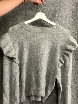 Stickad tröja - En stickad tröja med volanger på axlarna. Köpt från hm, tryck ej på köp nu skriv ist😁