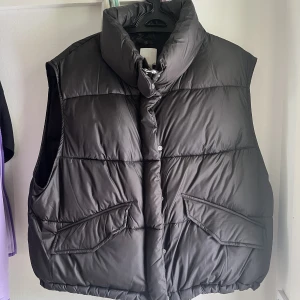 Svart väst - Svart väst från H&M i strl L. Det är både dragkedja och knappar på den och den går att spänna in i midjan. Använd fåtal gånger, ca 3, men skicket är som ny.