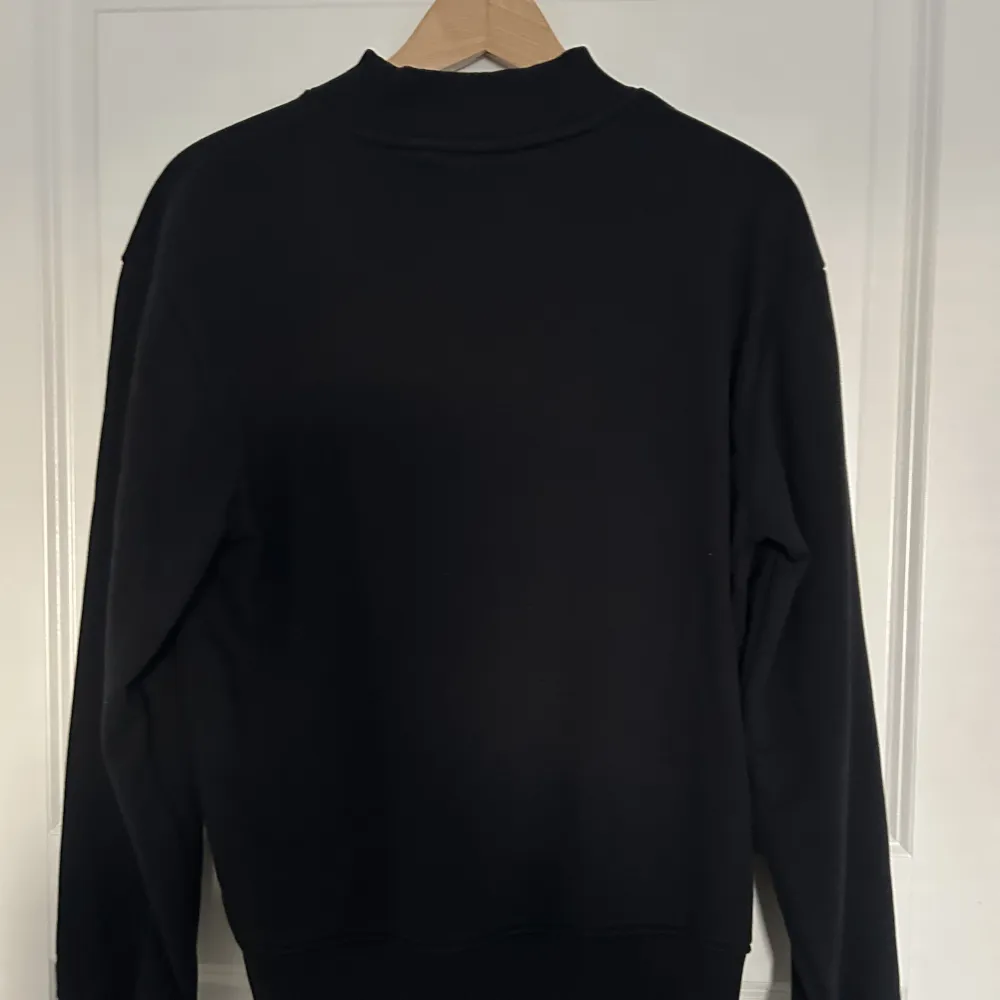 En svart tröja med ett litet Dickies märke på bröstet. Tröjor & Koftor.