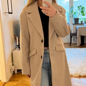 Beige kappa - Lång beige kappa från BERSHKA. Aldrig använd, fickor fortfrande osprättade. Storlek XS. 300:- ex frakt. 