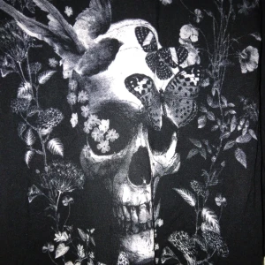 Svart längre topp med avklippta ärmar / linne. Döskalle tryck. Mjuk viskos. Strlk: XS-SMALL. Gina Tricot. - Svart längre topp med avklippta ärmar / linne.  Gina Tricot.  Döskalle tryck, även fåglar och fjärilar i trycket. Mjuk viskos. Strlk: XS-SMALL.