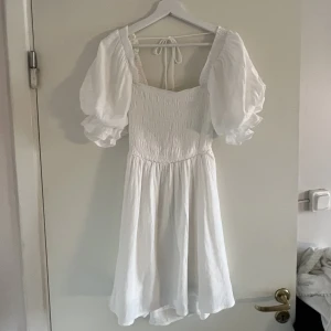 Student klänning - Vit klänning med puffiga armar och öppen rygg. Köpt från Princess Polly, oanvänd (prislapp kvar). Nypris 650kr+ frakt.