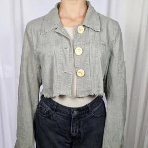 Jacka  - Ljusgrön tunn jacka med slitningar längst ned och linneliknande material 