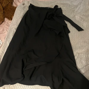 Långkjol - Kjolen går ner till mitten av smakbenen ungefär och är köpt från Gina Tricot för några år sedan. Den är omlott och har en knytdetalj i midjan samt en knapp på insidan. Använde kjolen mycket förut men väldigt bra skick.
