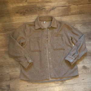 Teddytröja - Helt oanvänd teddytröja från NLY.  Rensar ur min garderob från en hel del oanvända kläder🌼 Kika och se om du ser något mer i min profil som du gillar så skickar jag med det till dig också!😊 Fler kläder kommer! 