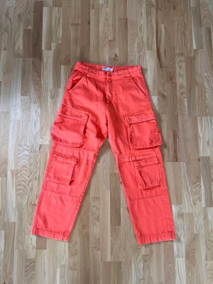 Cargobyxor orangea - Helt nya cargobyxor från bershka. Köpta för ca 6 månader sen men blev aldrig använda då det ej är min färg. Köptes för 550kr, säljer nu för 300kr! 