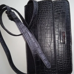 Svart väska  - Kommer inte till användning köparen står för frakten köpte för 250 och säljer för 50 den är rymlig skulle säger det för flats 4-5 iPhone 12 i.