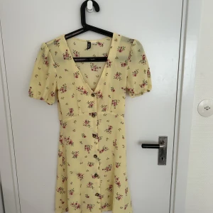 Crêppad sommarklänning med puffärm.  - Gul kort sommar klänning. Fin detalj med puffärm och v-rigning. Gjord i polyester och elastane. 