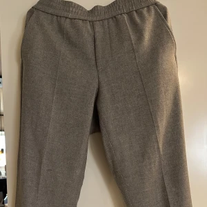Filippa K / kostymbyxor  - Säljer ett par schyssta kostymbyxor från Filippa K i storlek 50.  Byxorna är i en fin/tunn ull i färgen midgray. Byxorna har resår med snörning på insidan för bättre passform! Men ger även en väldigt avslappnad men ändå städad look.  Skicket är bra.