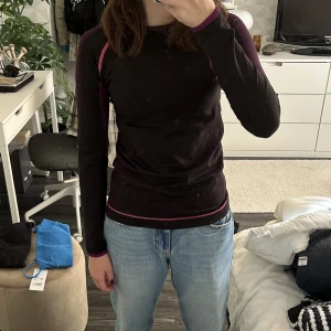 Underställströja  - Jag säljer en svart underställs tröja med lila och rosa detaljer och sömmar, tröjan är från h&m i storlek 158/164. Den är i hyfsat bra skick.