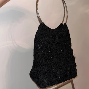 Virkad väska med paljetter - Säljer denna sjukt coola väska. Den är virkad i svart med paljetter på framsidan. Handtagen är två metallringar, i botten finns en platta och en fick i väskan.