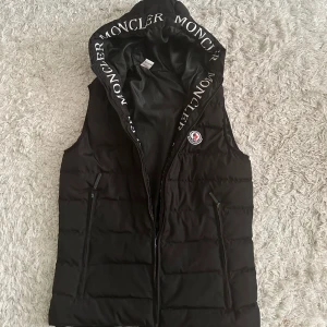 Väst - En moncler väst i simpel färg men unika ditaljer. Västan är använd nån gång, och är en moncler väst med allt den ska ha till och med scanner kan visa upp hela västen det är bara o fråga. Stora fickor med dragkedja vid sidan fullt fungerande.