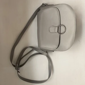 Väska - En grå söt väska inköpt på glitter för några år sedan. Legat nerpackad i en låda så nu är den lite sned men efter användning skulle jag tro att den blir som vanligt igen. 