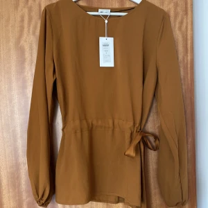 Söt topp från Vila Clothes - Söt topp jag köpt men aldrig använt, prislappen är kvar, den är i storlek 44 men den passar 38-40 med man kan tajta den i midjan med de bandet jag gjort till en rosett. Sista bilden är för att se vilken färg de är. Köpte för 349 men säljer för 100.