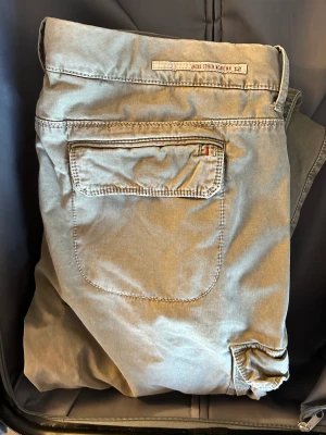 JACOB COHËN CARGOBYXA - Aldrig använda då jag köpte 2 par . Strl 40 men mer som 38. Cargobyxor med raka ben i beige stretchig bomull från JACOB COHEN med logotypplåster bak, bälteshällor, gylfknäppning, två diagonala fickor på sidorna och två sidfickor med lock. Gjorda i Italien