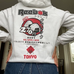 Hoodie Reebok med ryggtryck S - Vit hoodie med stort ryggtryck med sushi/japanskt tryck. Använd några gånger och i fint skick. Har två ljusrosa, knappt synliga fläckar på nedre höften (se tredje bilden) 🥰