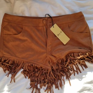 Frans shorts - Shorts med fransar i cowboy stuk. Oanvända med lapp kvar så i bra skick. Köparen står för frakt. 