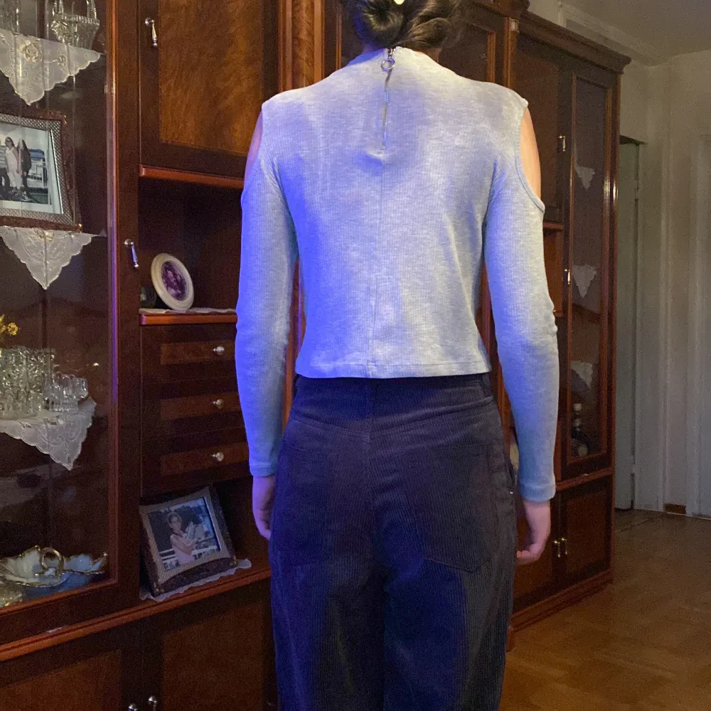 Långärmad highneck cold-shoulder tröja i grå med dragkedja vid ryggen. Storlek S.. Toppar.