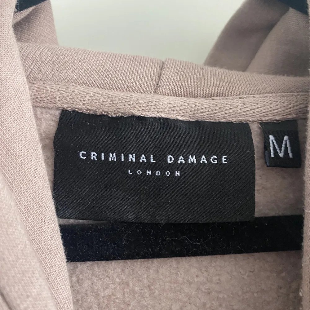 En beige/rosa croppad hoodie från Criminal Damage. Den är använd en gång så den är i väldigt bra skick. Den blir tvättad innan den skickas. Skriv för fler bilder😊. Hoodies.