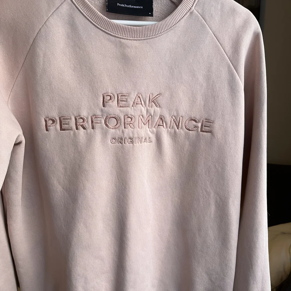 Ljusrosa sweatshirt från PeakPerformance. Nyskick men den fick tyvärr någon fläck efter tvätten. Neuletakit & Villapaidat.