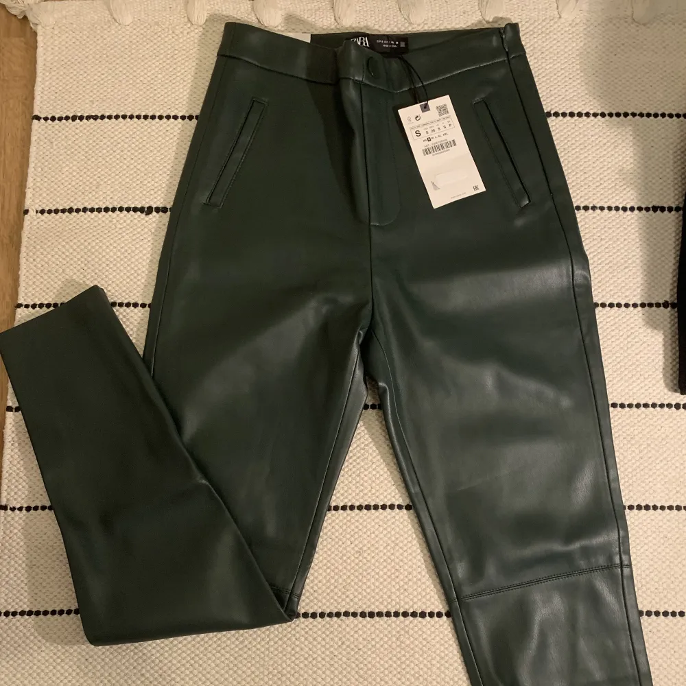 Mörkgröna skinnleggings från Zara, storlek S. Ej använda, prislapp fortfarande kvar. Högmidjade, dragkedja vid sidan.. Jeans & Byxor.