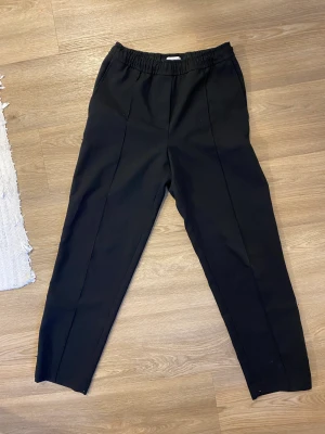 Svarta kostymbyxor - Svarta kostymbyxor från Weekday, länge varit en favorit i garderoben.  Man kan välja att ha slits längs ner eller stänga dragkedjan. Funkar både high och low waist! Nyckelplagg i garderoben som funkar till allt!