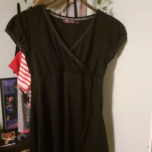 Svart topp - Svart topp med v- rigning där tyget går omlott om varandra. Korta ärmar och fina detaljer. Stirlek L men lite mindre i storleken och padsar för S/M. Mycket bra skick.🌸