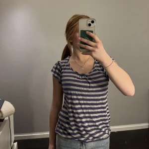 Randig grå lila t-shirt - Jätte söt grå lila randig t-shirt med öppning och grått tyg vid ryggen. Kommer inte till användning. Nyskick❤️❤️