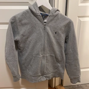 Polo Ralph lauren zip hoodie storlek 14 -16 år - Väl använd tröja i bra skick, använt den ett fler tal gånger men nu på senaste mest hängt i garderoben, därför jag säljer den.  Tröjan är i storlek 14-16 år.