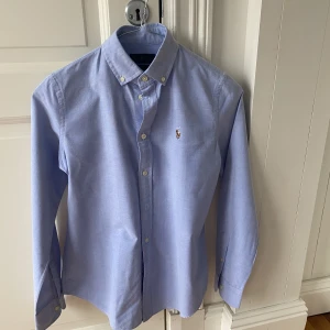 Ljus blå Ralph Lauren skjorta  - Ljus blå Ralph Lauren strkl 4 (US size) sitter ungefär som en S. Slim fit light weight Oxford. Helt oanvänd. 