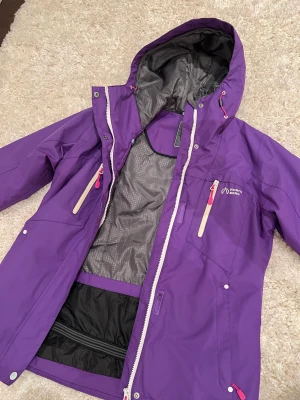 Skidjacka - North Bend - Lila skidjacka från North Bend i storlek 38. Jackan är använd två säsonger men är fortfarande i fint skick. Kan finns några mindre fläckar, men inga förslitningsskador.  Jackan har snölås.  Skriv för mer information.