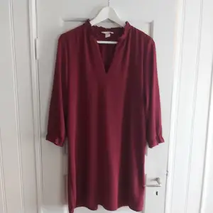 Vinröd klänning med trekvartsärm och v-ringning. Liten volang längs hals och ärm. Från H&M