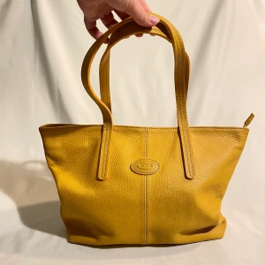 Gul tote bag från TOD’s - Befintligt skick. Några små fläckar på insidan men annars ser oanvänd ut på utsidan. Gedigna och välfungerande dragkedjor. 
