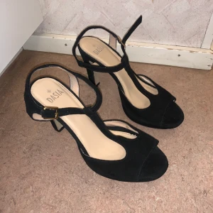 Svarta sandaletter från märket Dasia stl 37 - Svarta klackskor från märket Dasia i storlek 37. Använda ett fåtal gånger och är i gott skick. Kostade från början 879kr men säljs nu för 250kr.  Klackhöjd ca 12cm. Jag kan mötas upp i Stockholm men även skicka skorna, dock står du för frakten.