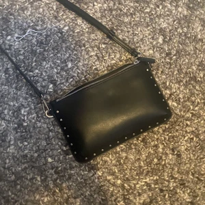 Svart väska med detalj - Väldigt fin väska, knappt använd. Många fack inuti. Väldigt trendig 😻 både jeansen och tröjan hittar ni i egna annonser 💓 frakt tillkommer! 🥰