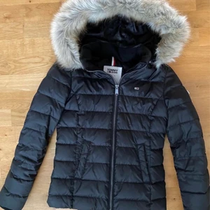 Vinterjacka Tommy Hilfiger - Fin vinterjacka med luva. Både pälskant på luvan och luvan går att knäppa av. Muddar i ärmslut. Sparsamt använd en halv vinter. Storlek XS. Inköpt på NK i Göteborg. Garanterat äkta Tommy Hilfiger.
