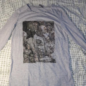 Långärmad tröja med abstrakt tryck - Grå tröja med abstrakt tryck. Strl s, den är ganska lång dock men sitter bra på kroppen, använd men bra skick