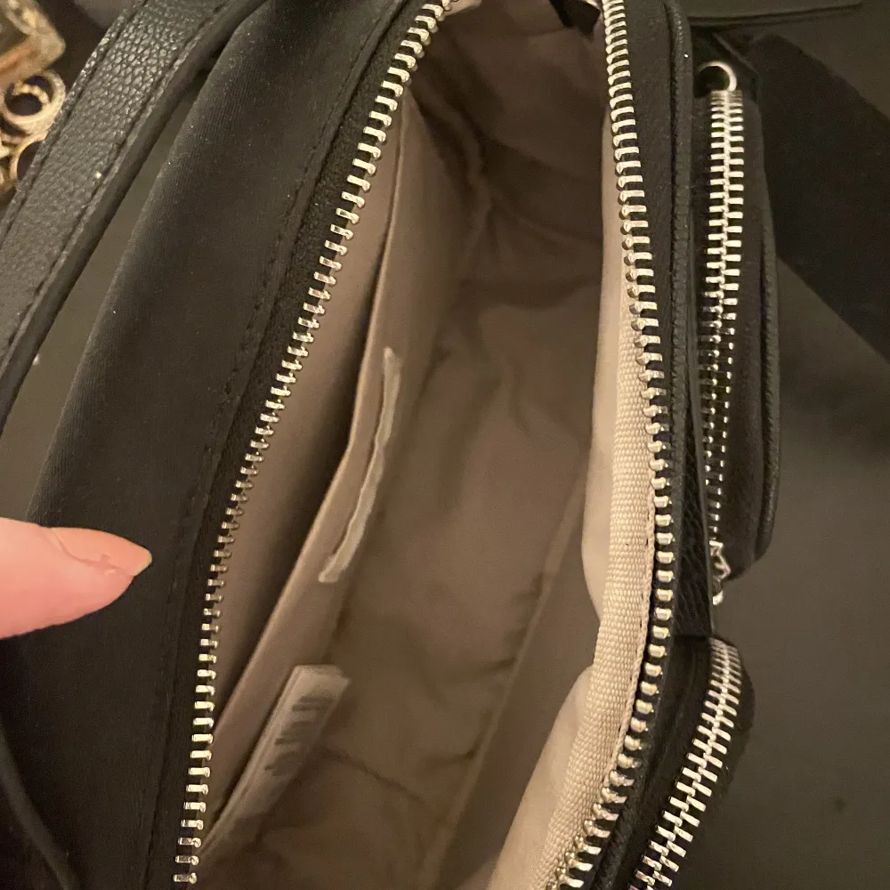 Svart handväska från H&M med ett stort fack och två små fack framme på väskan. Justerbart band så den kan vara både kortare och lite längre!. Accessoarer.