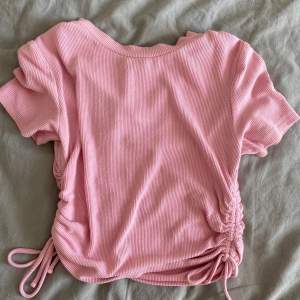 En rosa tröja med snören på sidan från Bikbok storlek Xs köpt för 125kr säljs för 60kr använd ett par gånger 🫶🏻