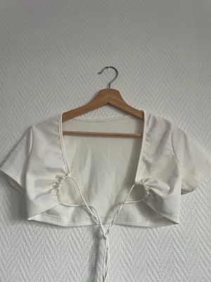 Crop top  - Vit crop top som man kan ha på båda hållen, knyta fram till eller bak i ryggen  Upplever inte den genomskinliga 