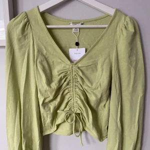 Topp - Grön topp med en liten puffärm med resår längst ner på armarna🥰aldrig kommit till användning så prislappen är kvar!