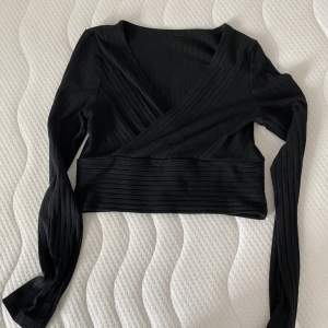 Säljer en svart omlott, v-ringad, croppad tröja i ribbat material. I fint skick. Kan skicka bild med tröjan på mot förfrågan. 50+frakt 