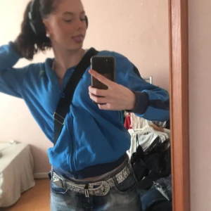 puma zipup - mörkblå puma zipup med en rand på varje ärm. det står puma i gröntext på nedre kanten längst bak samt därframmepå bröstet. supercool!