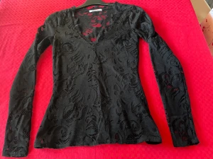 Svart V-ringad ,  långärmad spetstop - Stretchigt material  Etiketten om materialet är bortklippt  Fodrad från bysten och neråt och insvängd i midjehöjd 58 cm lång  Använd vid två tillfällen  Bra skick  Gina Tricot i XS 