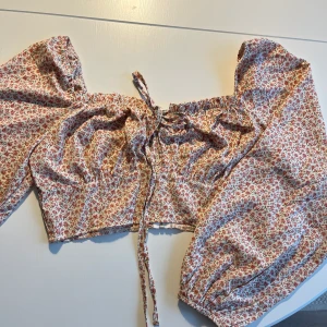 Somrig topp - Jättefin blommig tröja med knytning! Ganska kort i modellen, har dragkedja bak. Balongärmar. Aldrig använd så nyskick!☺️